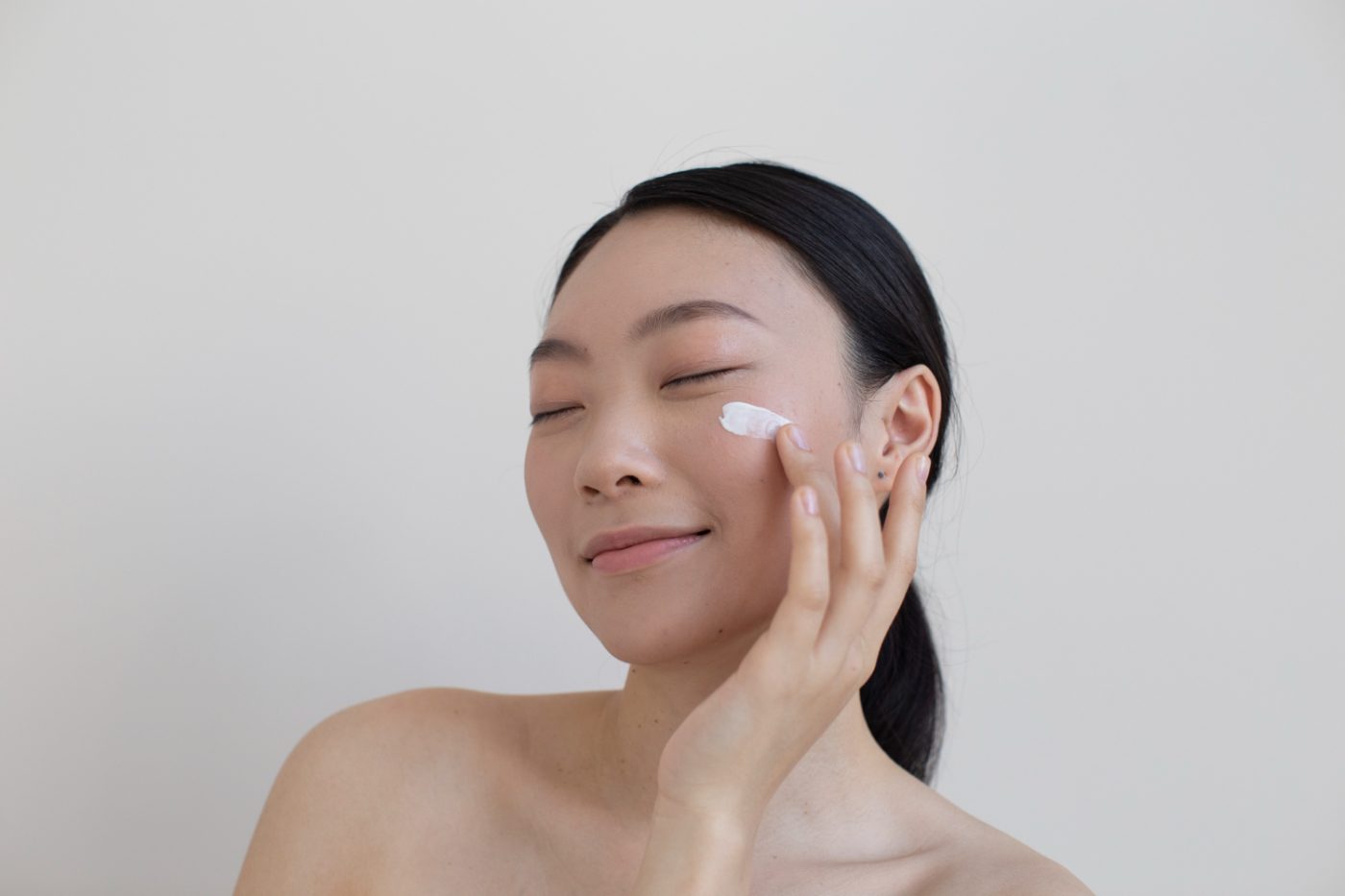beautiful asian woman posing with facial cream e1655949293503